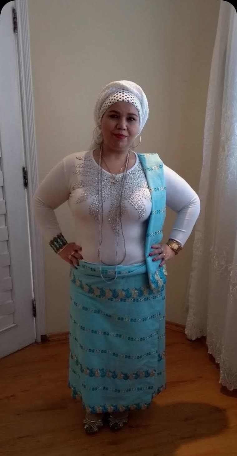 Mãe de santo do Canto da Oxum vestida de branco e azul, com torço na cabeça e guias de contas